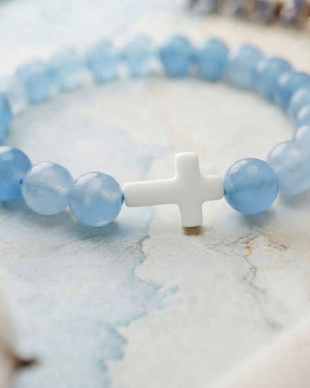 Gros plan sur la croix blanche du bracelet bleu clair