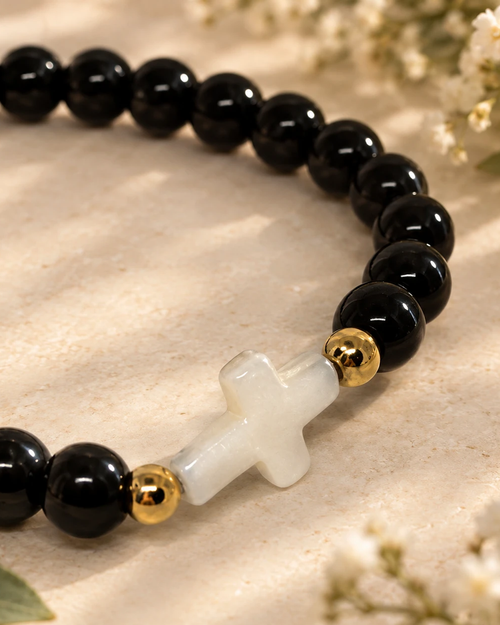 Gros plan sur la croix nacrée du bracelet Noir et Doré
