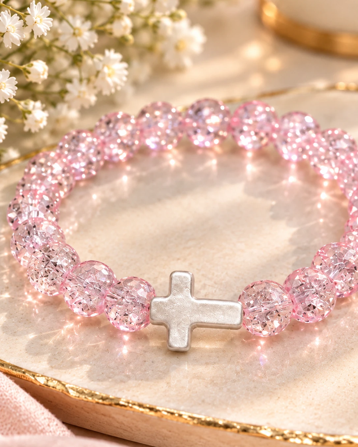 Gros plan sur la croix blanche du bracelet rose éclat cristal