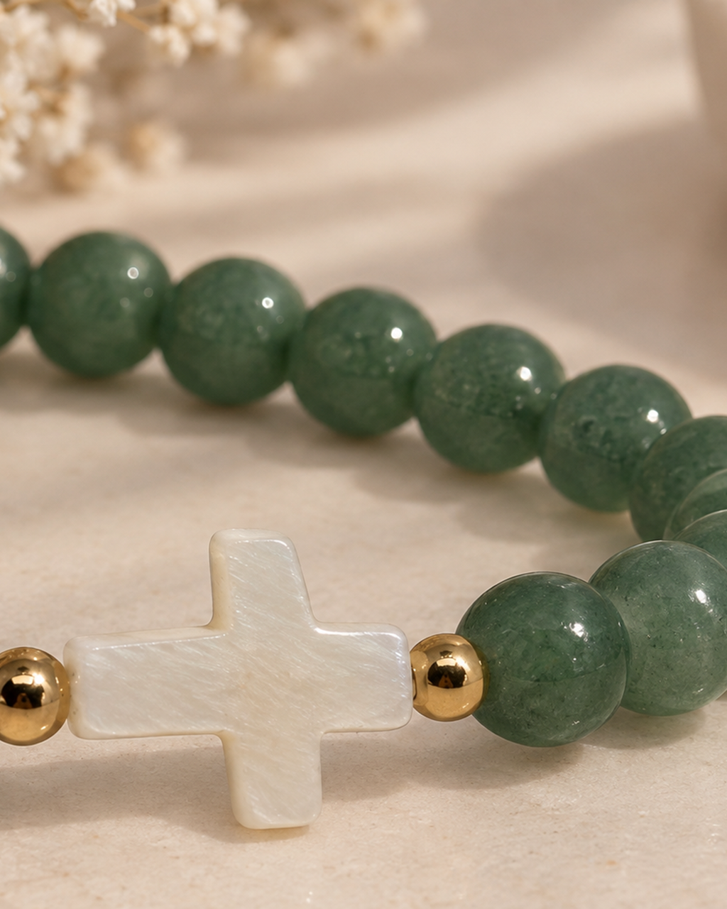 Gros plan sur la croix en nacre du bracelet vert et doré